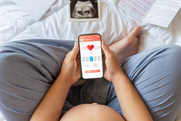 Pregnancy health app. Pregnant woman holding smartphone. Mobile pregnancy online maternity...