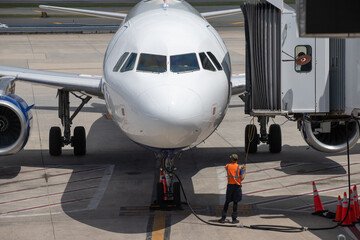 Employé d'aéroport en train de manœuvrer la passerelle d'embarquement d'un avion