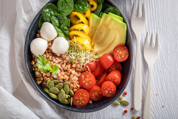 Healthy salad with avocado, tomatoes, cheese and groats.