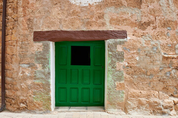Fototapeta na wymiar Stone facade with small old wooden door painted green