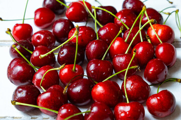 Obraz na płótnie Canvas Fresh red cherry, pile of cherries with stems and leaves close-up.