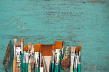 Paint brushes with palette knives on blue background
