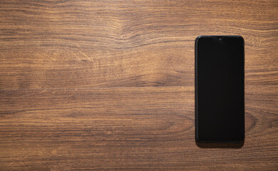 Black smartphone on the wooden background.