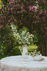 Still life of country flowers and country dishes on a table with an old tablecloth
