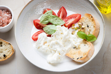 Plate with stracciatella or cheese produced from italian buffalo milk, middle closeup, studio shot on a beige stone background