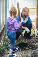 adults and children do household chores together, clean and tidy. dad and little girl clean leaves and garbage in the yard
