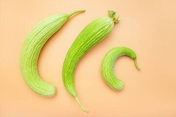 Three fruits of unusual and rare delicacy - an Armenian cucumber or snake melon on orange background. A fresh and delicious product for a healthy diet