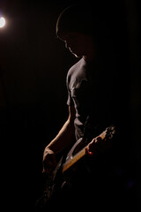 Fototapeta premium man playing the guitar in the dark with one spotlight
