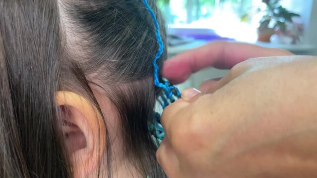 blue braids with kanekalon Zizi in the hands of a hairdresser, creativity and fashionable hairstyle concept, braiding african braids for a girl in a beauty salon