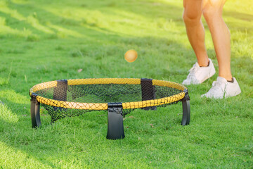 Playing ball with mini beach volleyball net on a green grass lawn. Modern Leisure sports and fun recreation with friends - Powered by Adobe