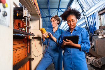 Engineer african and cauasian woman wearing safety helmet working and checking machine  automotive part warehouse. Factory for the manufacture and processing.