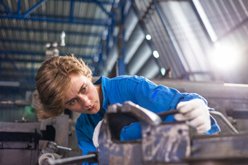 Fototapeta premium Young female worker in protective uniform operating machine at factory Industrial.People working in industry.Manufacturing plant on background