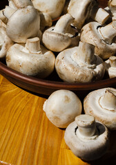 Fresh champignon mushrooms on a ceramic plate, close-up.