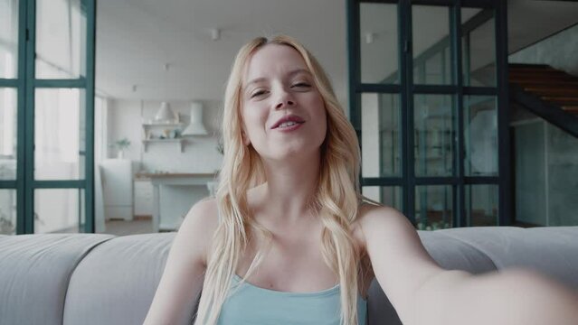 Happy pretty blonde woman smiling face waving hand talking to webcam make video call at home talking chatting by virtual video call zoom app online videocall meeting. Female or blogger having video