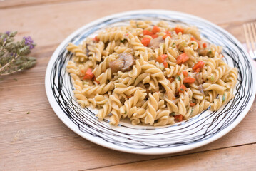 fusilli pasta with carrot and mushrooms on a wooden table