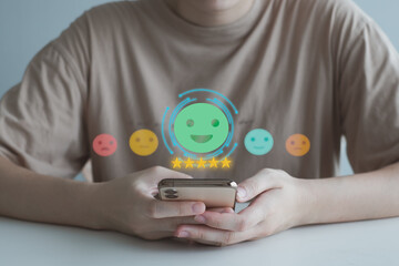 Hand holding mobile smartphone and select happy face for feedback service rating experience. Satisfaction survey with negative, neutral and positive facial expressions. Business rating experience.