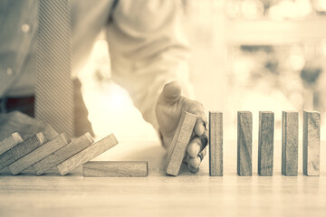Close-up hand prevent wooden block not falling domino concepts of financial risk management and...