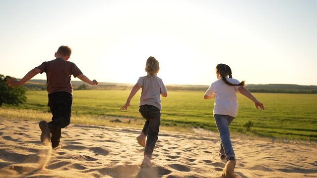 Children boys and girls run on sand. Children play at sunset.Happy family in nature. Run to success and victory. Children play in sand in summer.Healthy lifestyle. Vacation and family travel in summer