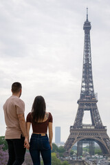Young couple in love looking at the eiffel tower in paris from afar.