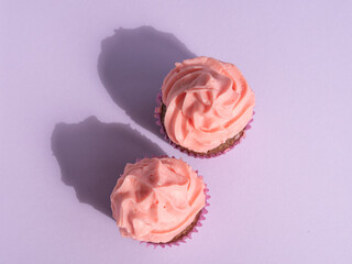 Two cupcakes on a purple background with space for text, top view