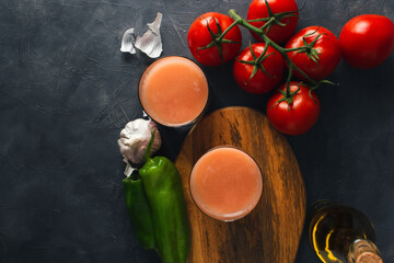 Top view of typical spanish tomato soup (andalusian gazpacho) with fresh tomatoes, green peppers, garlic and olive oil. Glass of delicious gazpacho with copy space.