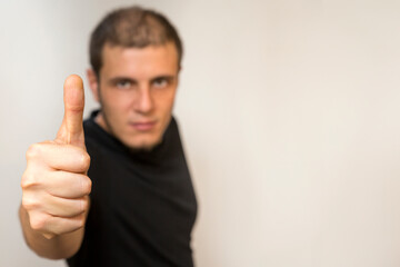 Boy on a white background. Caucasian white man with short hair and black eyes. He makes the ok sign.
