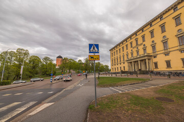 Fototapeta na wymiar Beautiful view of roadway with crosswalk sign against backdrop of urban landscape with grey sky background. Sweden. 