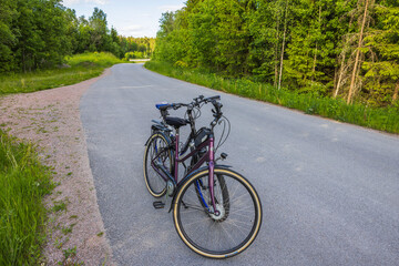 Fototapeta premium Close up view of two bicycles isolated on asphalt road with forest landscape on background. Sweden.