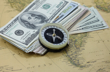 Classic round compass and american dollars on background of old vintage map of world as symbol of tourism with compass, travel with compass and outdoor activities with compass