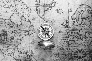 Classic round compass on background of old vintage map of world as symbol of tourism with compass, travel with compass and outdoor activities with compass