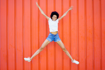 Happy black woman jumping on street