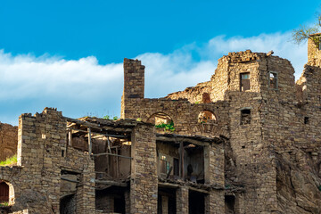 ruins of stone houses attached to the rock in the depopulated village of Gamsutl in Dagestan