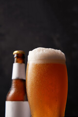 Bottle and glass of beer on black background.