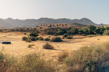 Building in semi-desertic landscape at sunset, with mountains in the horizon