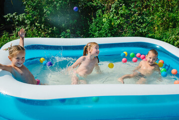 Happy cute children, preschoolers, bathe in the summer in the village in inflatable pool, make...