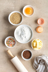 Fototapeta premium Baking ingredients: flour, eggs, sugar, butter, cocoa, rolling pin and spices on a beige background. View from above. Space for text