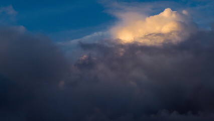 Fototapeta na wymiar Teintes orangées sous des cumulus, par temps pluvieux, en fin de journée