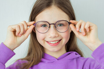 Pretty little girl in colored-rimmed glasses. Glasses for children. Diagnostics and correction of vision. Advertising of an ophthalmological clinic and an optics store - obrazy, fototapety, plakaty