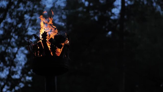 Crown on a pillar with fire. Close-up of a fire on a pole. A cinematographic picture. Soft focus on objects. Pagan bonfire festival in Latvia Summer night Ligo. Midsummer bonfire on a pole.