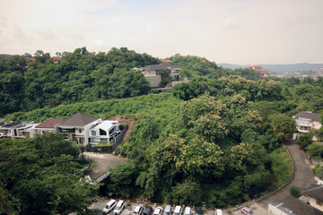 Cityscape buildings view from above with natural green forest trees mountain as part of the scenery