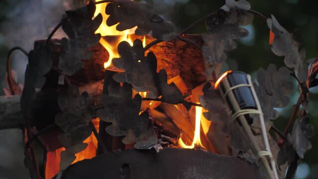 Crown on a pillar with fire. Close-up of a fire on a pole. A cinematographic picture. Soft focus on objects. Pagan bonfire festival in Latvia Summer night Ligo. Midsummer bonfire on a pole.