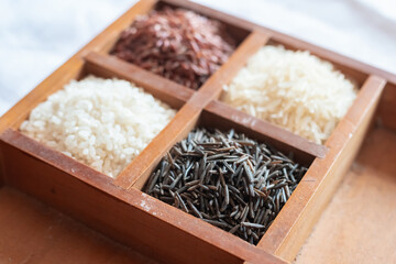 wooden box with four sections filled with assorted basmati rice red, white black selective focus