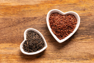 brown and black rice long in a white plate in the shape of a heart close up