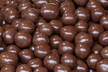 dragee chocolate, nuts in glaze background dark confectionery