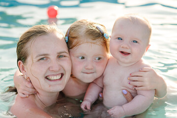 Mother and kids having fun in the swimming pool. Summer leisure and family holidays and vacation...
