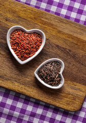 rice white and red in white in a plate in the shape of a heart on a wooden background top view