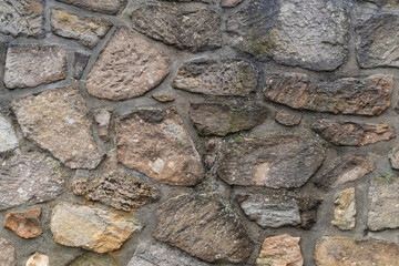 stacked stone wall of uneven blocks, old and weathered background