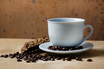 Cup of coffee with coffee beans on a wooden table. White cup with espresso coffee. Background for a coffee shop. Arabica.