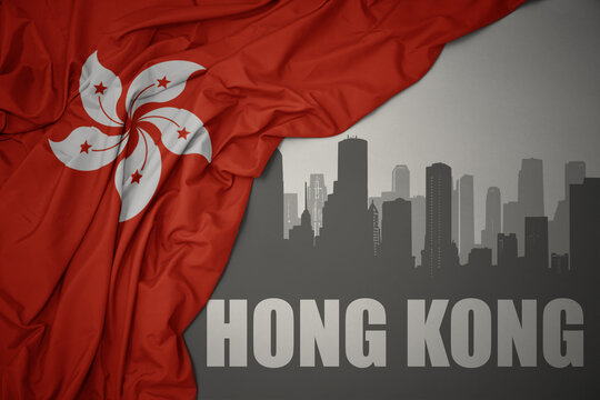 abstract silhouette of the city with text Hong Kong near waving national flag of hong kong on a gray background.3D illustration
