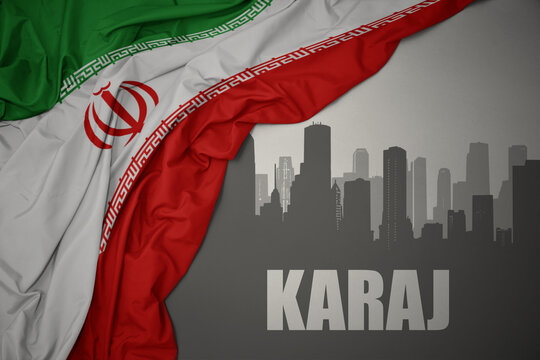 abstract silhouette of the city with text Karaj near waving national flag of iran on a gray background.3D illustration